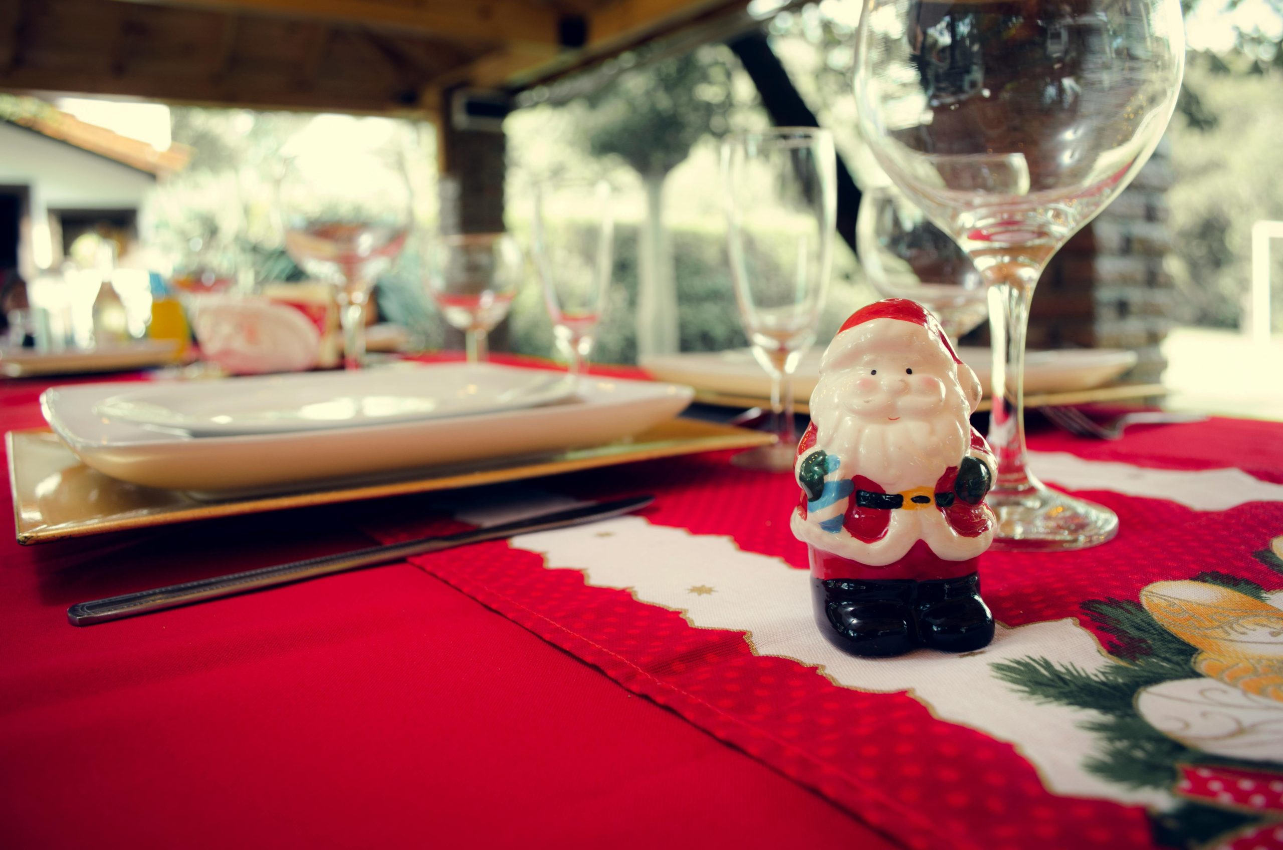 A cheerful Santa figurine decorates a festive table setting ready for a Christmas celebration.